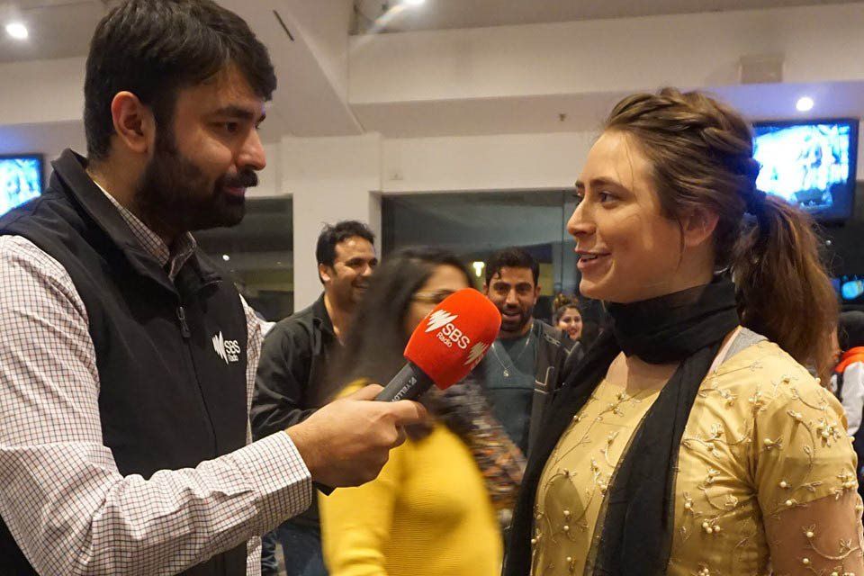 A man is interviewing a woman with a red microphone.