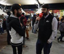 A man is holding a microphone and talking to another man.