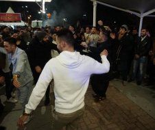 A man in a white hoodie is dancing in front of a crowd of people.