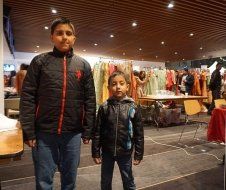 Two young boys are standing next to each other in a room.