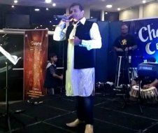 A man is standing on a stage singing into a microphone.