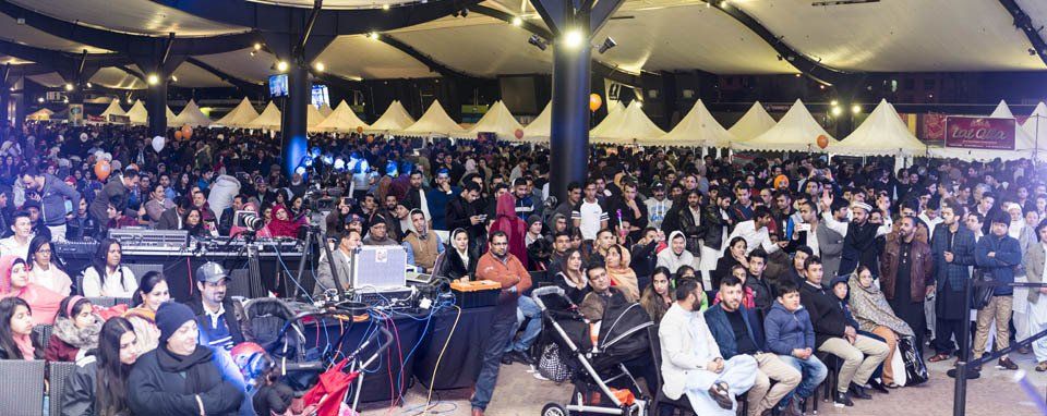 A large crowd of people are sitting in a large room at a concert.