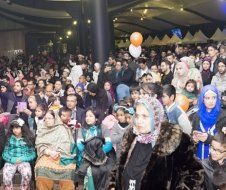 A large group of people are sitting in a room with balloons.