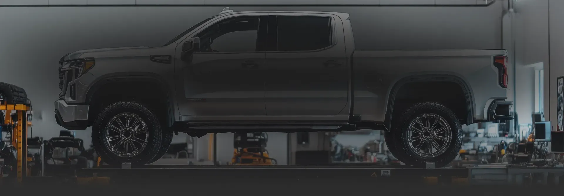 Silver truck raised on lift in garage | DeMartile Auto Care & Tires