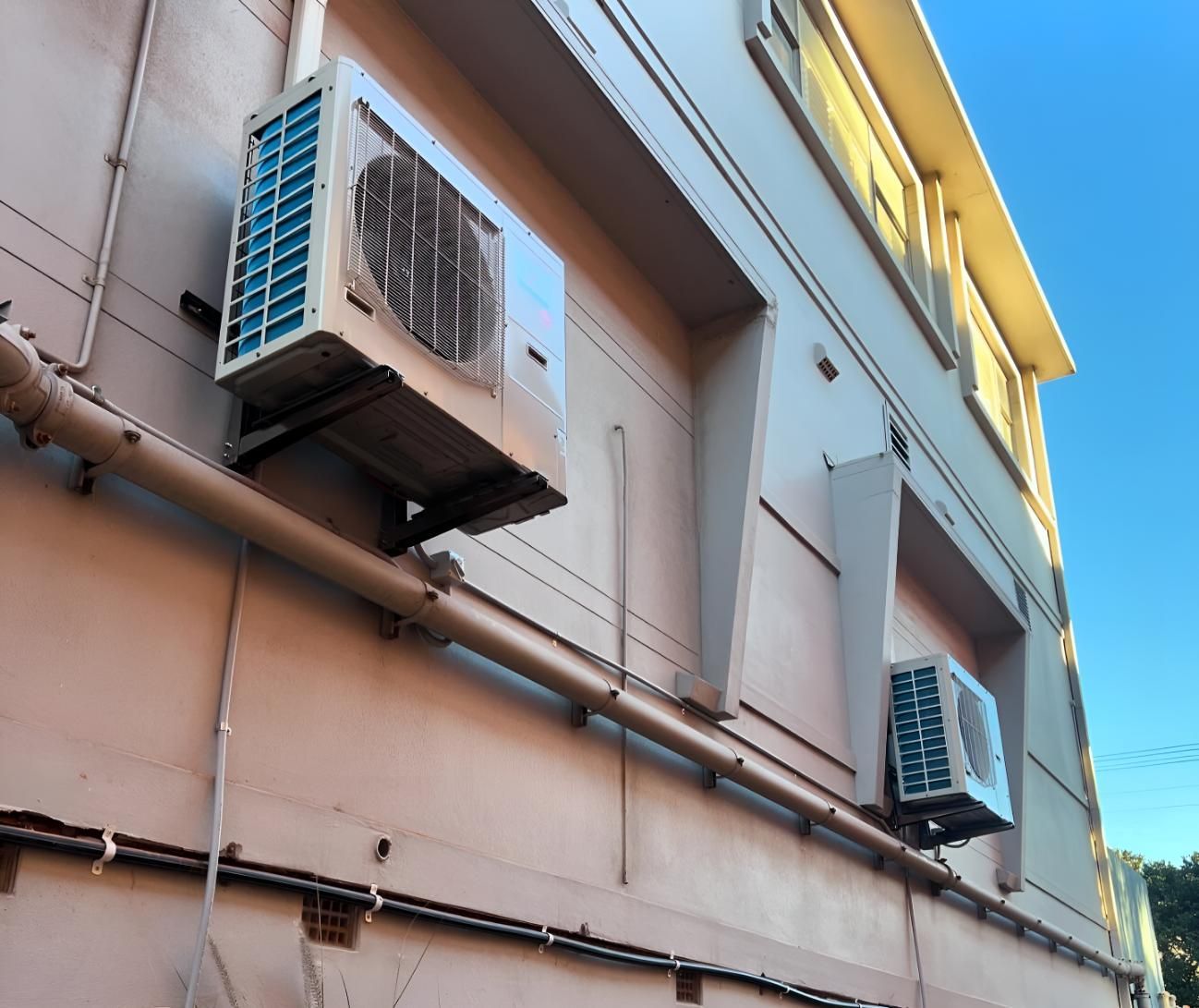 Three Air Conditioners Are Mounted on the Side of a Building — Kiama Air Conditioning in Albion Park Rail, NSW