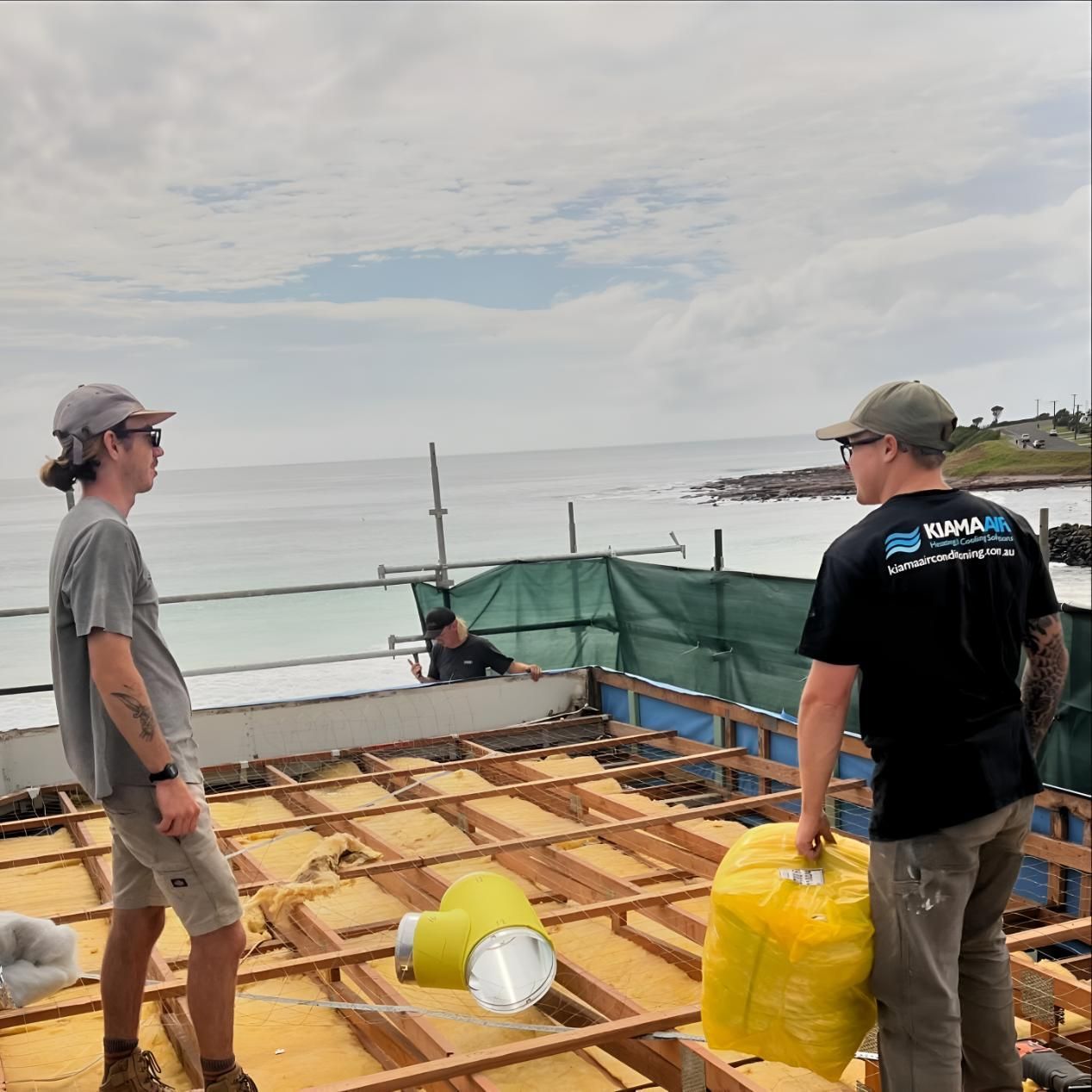Two Men Are Standing on Top of a Wooden Structure — Kiama Air Conditioning in Albion Park Rail, NSW