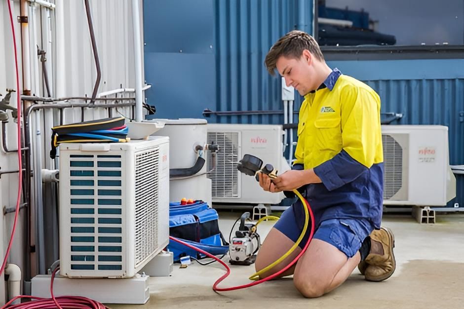Man is Kneeling Down Working on an Air Conditioner — Kiama Air Conditioning in Albion Park Rail, NSW