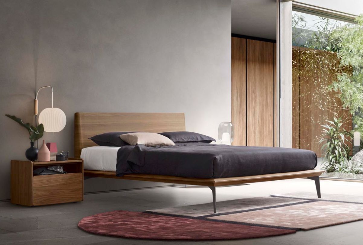 Struttura del letto in legno in una camera da letto minimalista con una grande finestra e un tappeto.