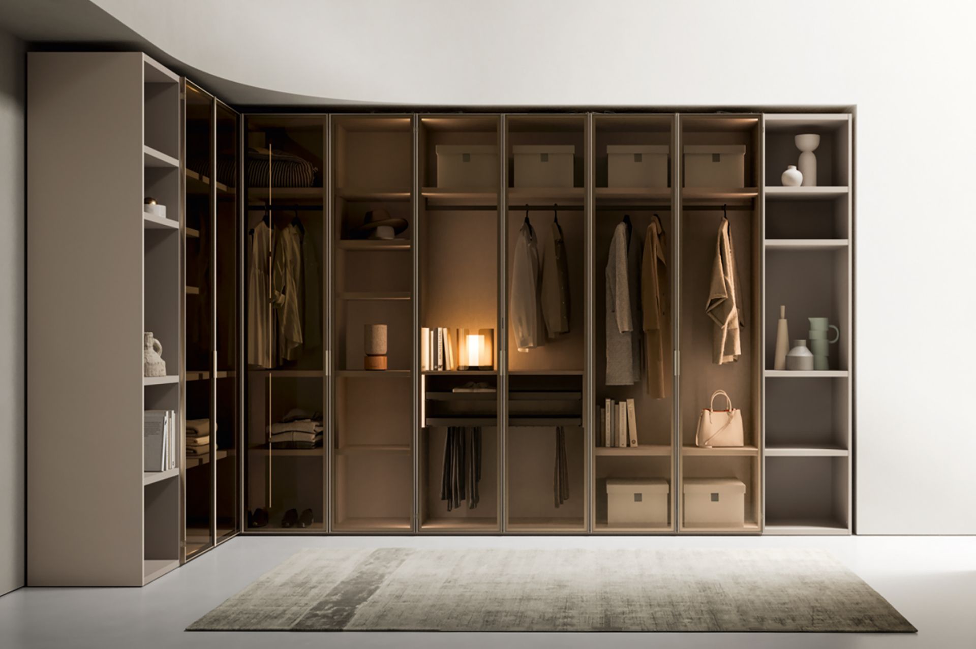 Cabina armadio aperta con ripiani, appendiabiti, cassetti e illuminazione beige sopra un tappeto.