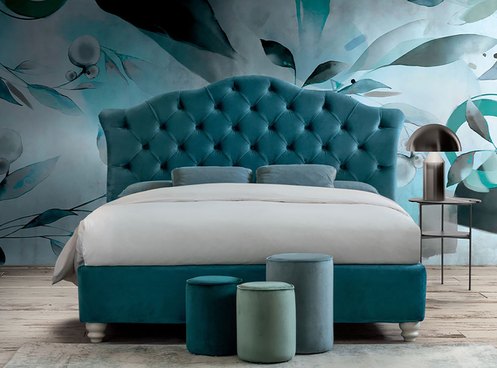 Letto trapuntato color verde acqua con lenzuola bianche in una camera da letto moderna con carta da parati a motivi di foglie.