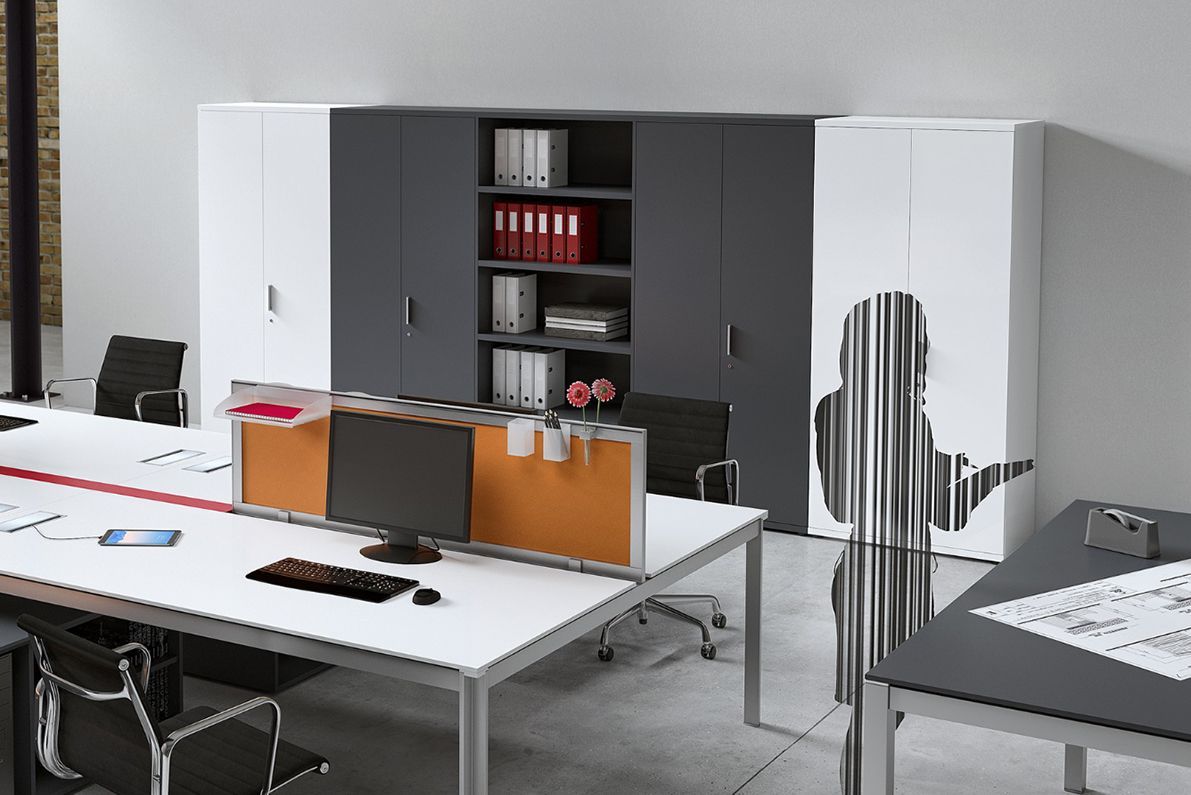 Spazio ufficio con scrivanie bianche, schedari e divisori per cubicoli.