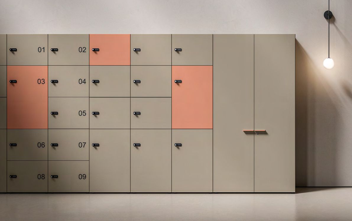 Armadietti beige con dettagli corallo e maniglie nere, illuminati da una lampada sospesa.