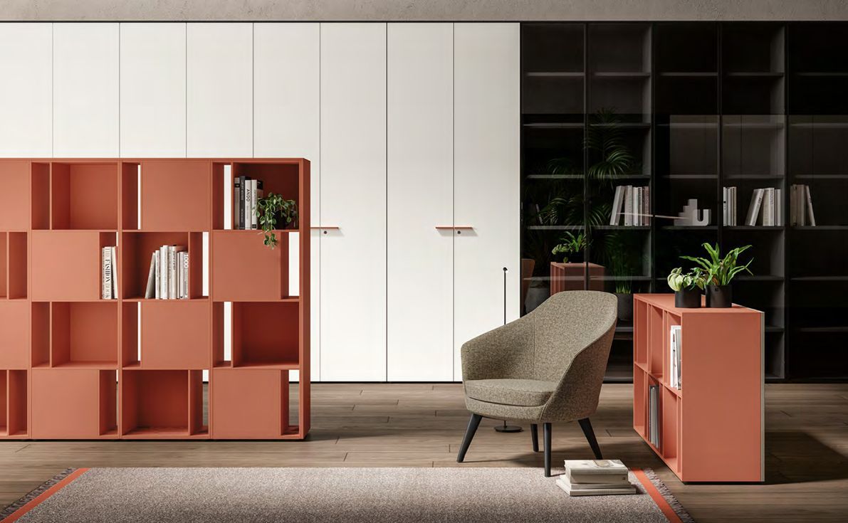 Soggiorno moderno con scaffali color corallo, ante bianche dell'armadio e una poltrona a fantasia.