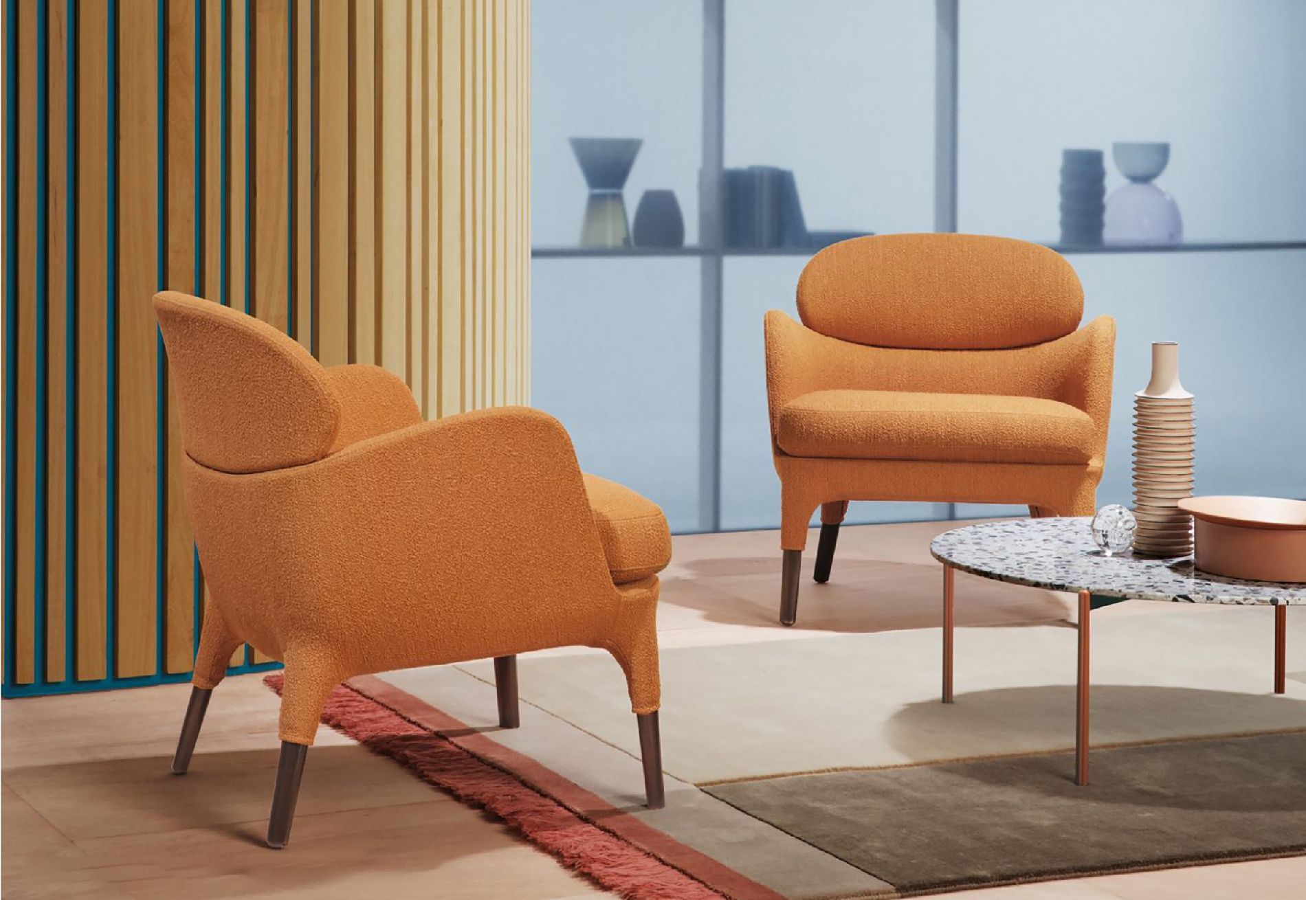 Sedie imbottite arancioni in un soggiorno moderno con tavolino da caffè e arredamento neutro.