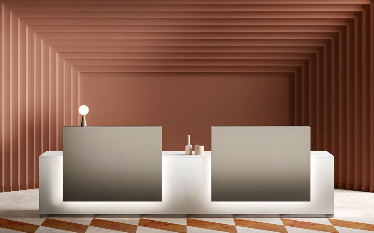 Bancone della reception con due pannelli retroilluminati in uno spazio color pesca con pareti a coste e pavimento in piastrelle decorative.