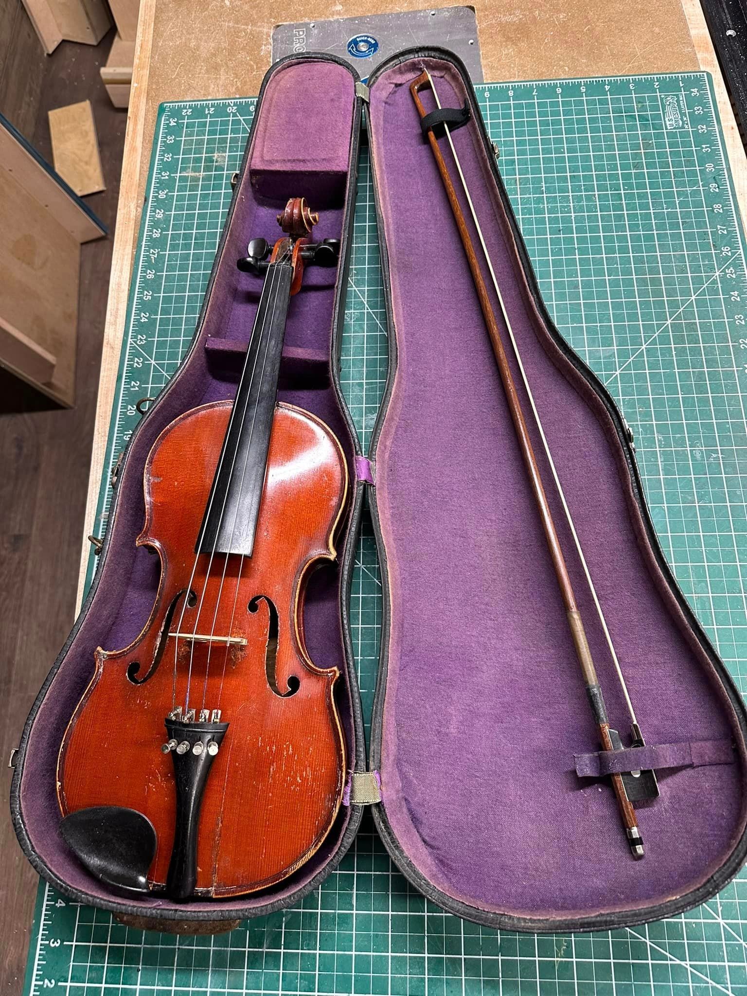 A violin and bow are in a purple case on a table