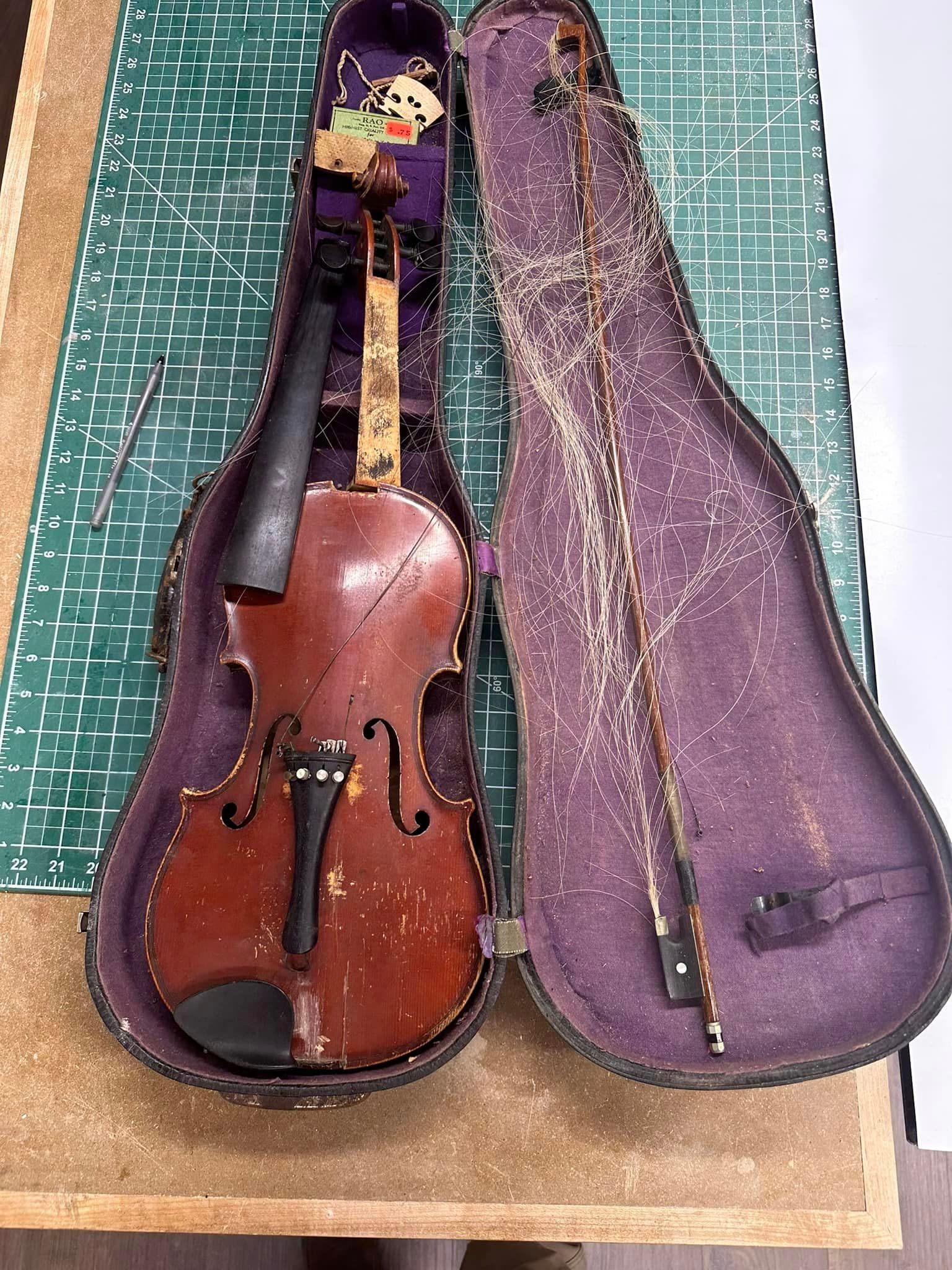 An old violin is sitting in a purple case on a table