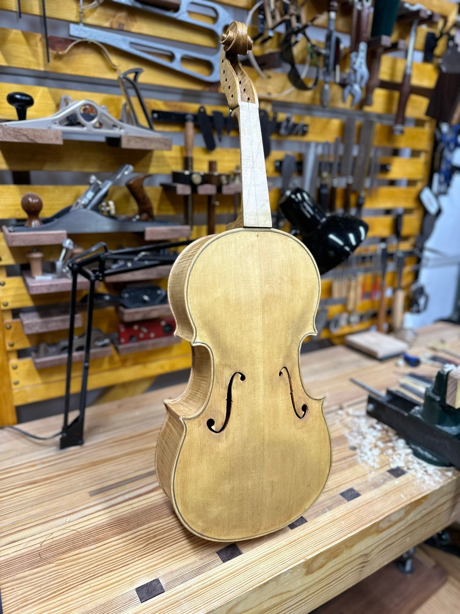 A violin is sitting on a wooden table in a workshop