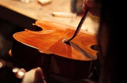 A person is polishing a violin with a brush