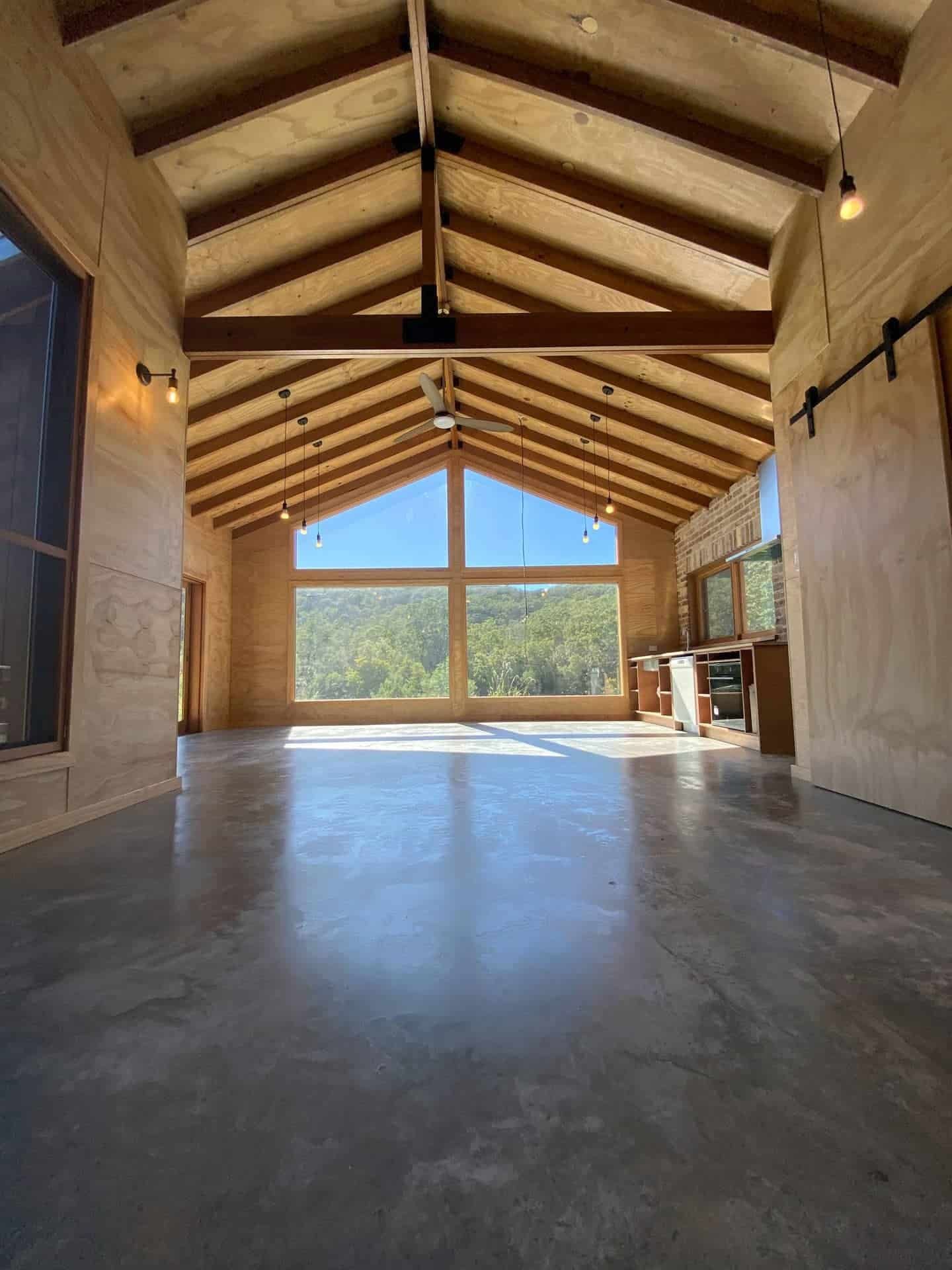 A Large Empty Room with A Wooden Ceiling and Concrete Floor — Blue Horizon Projects in Bateau Bay, NSW