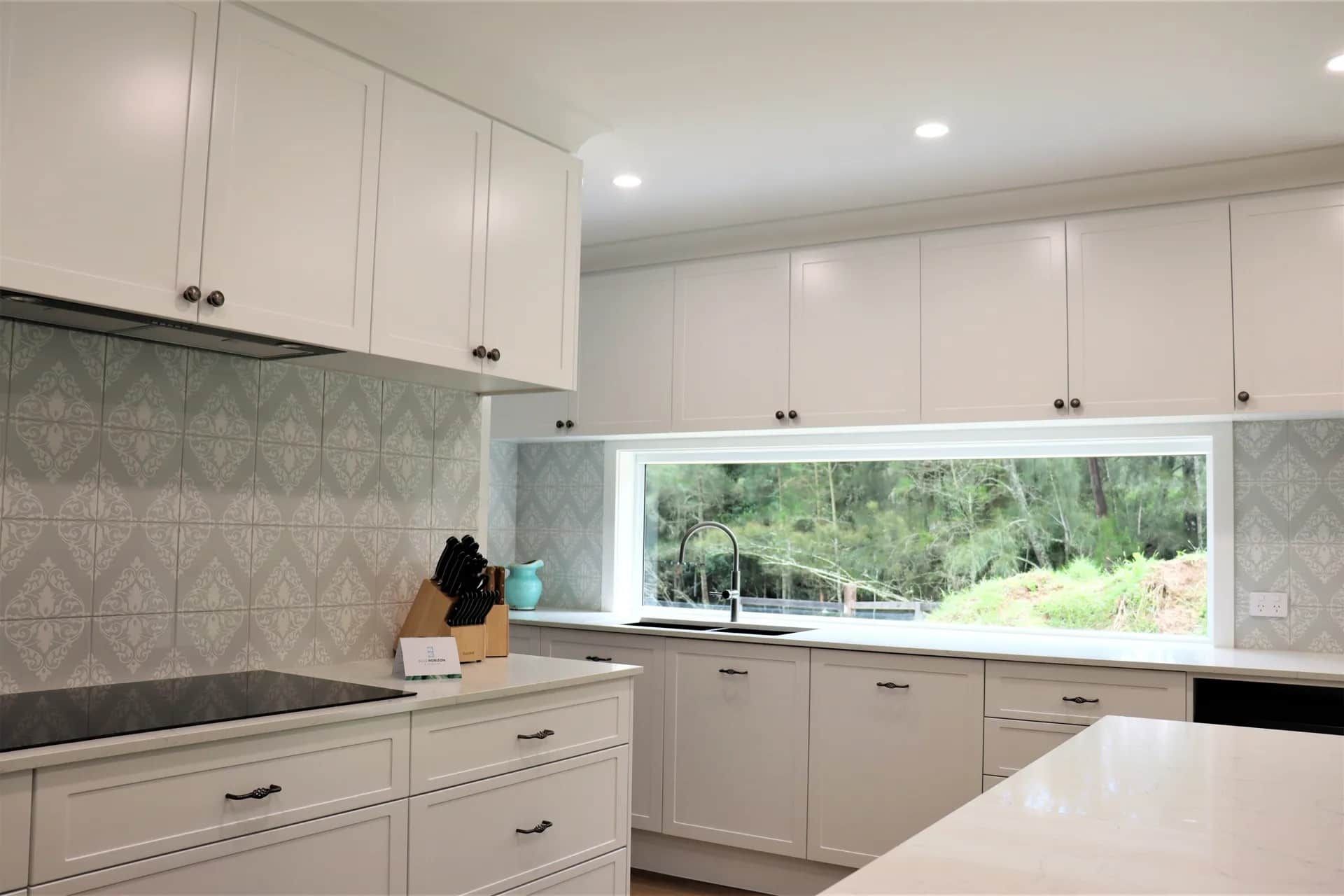 Modern Kitchen with White Cabinets, Patterned Backsplash and A Sleek Black Faucet — Blue Horizon Projects in Bateau Bay, NSW