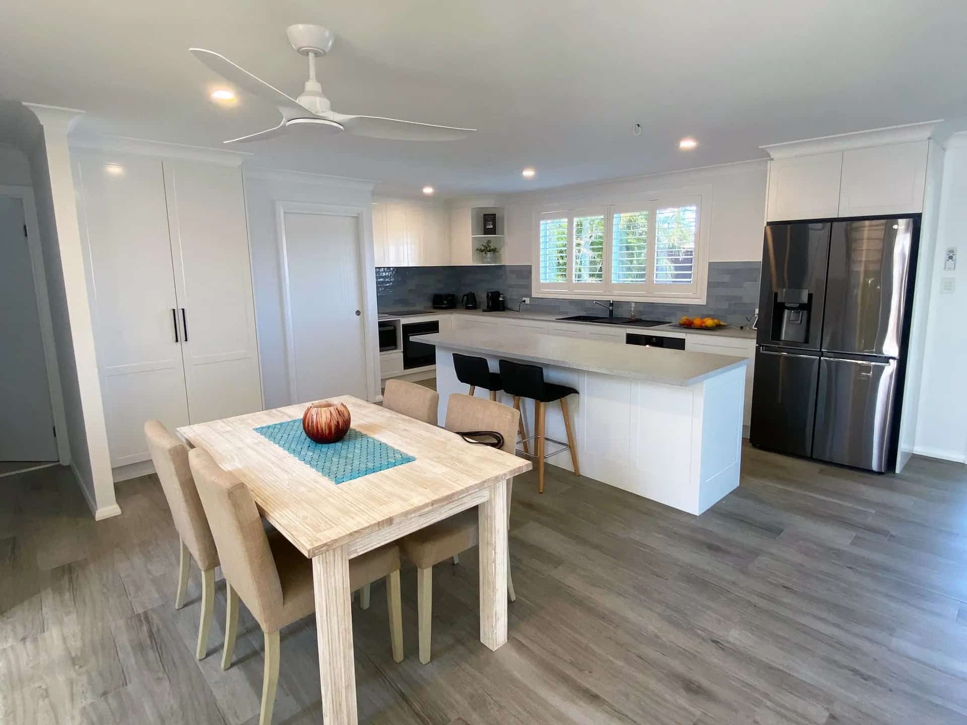 A Kitchen with A Table and Chairs and A Ceiling Fan — Blue Horizon Projects in Bateau Bay, NSW