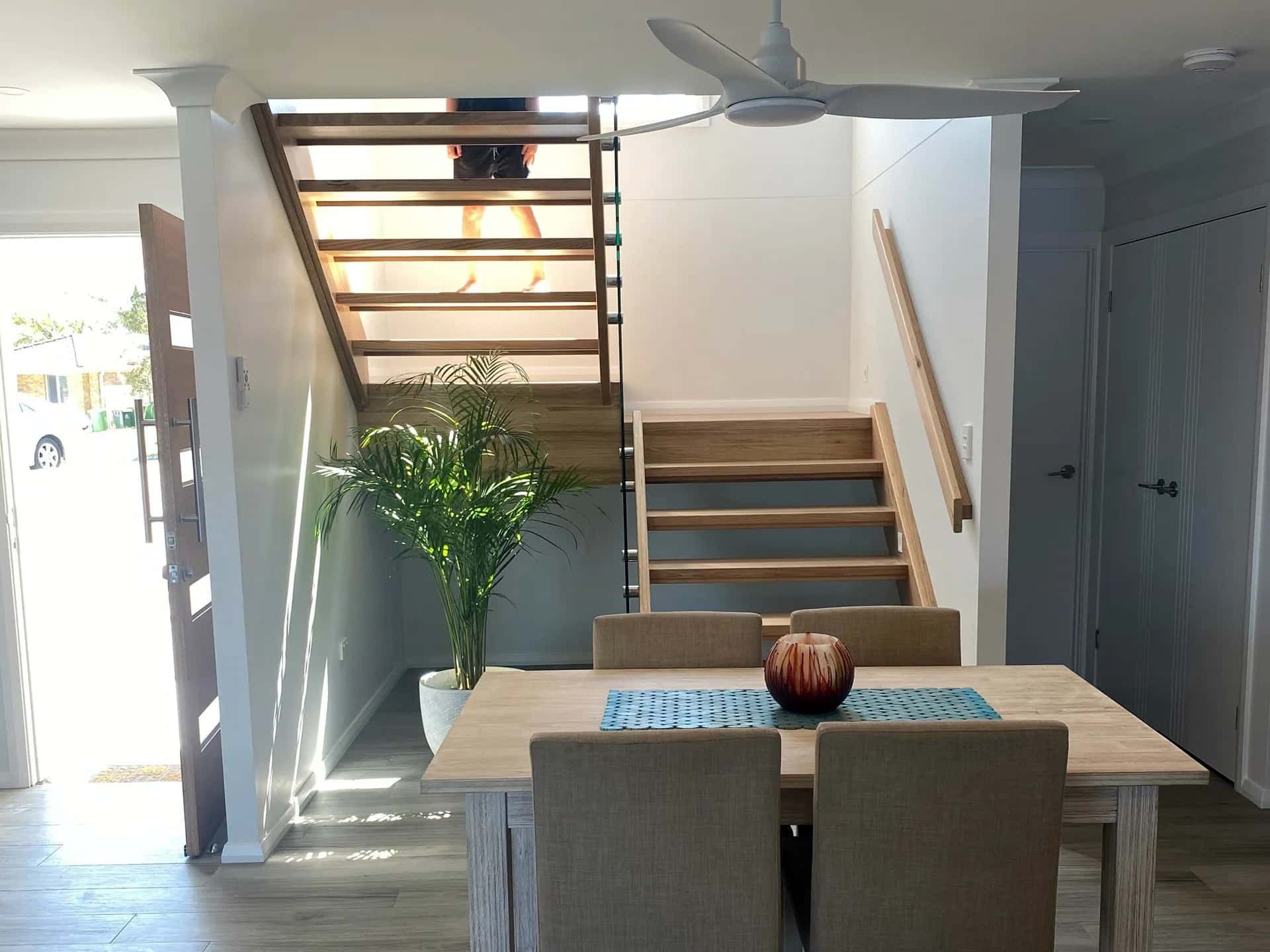 A Dining Room with A Table and Chairs and Stairs — Blue Horizon Projects in Bateau Bay, NSW