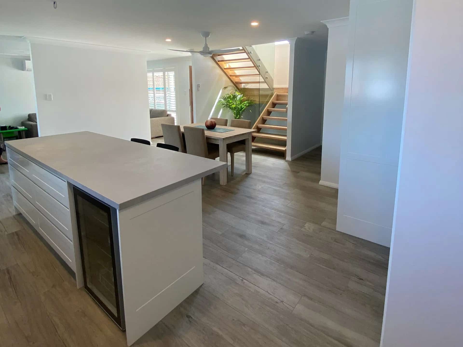 A Kitchen with A Large Island and A Staircase in The Background — Blue Horizon Projects in Bateau Bay, NSW