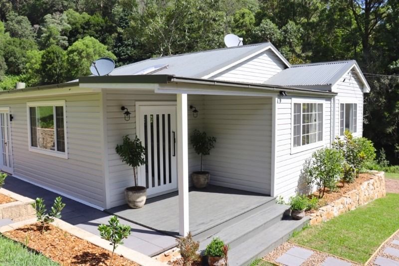 A Small White House with A Porch and Trees in Front of It — Blue Horizon Projects in Bateau Bay, NSW