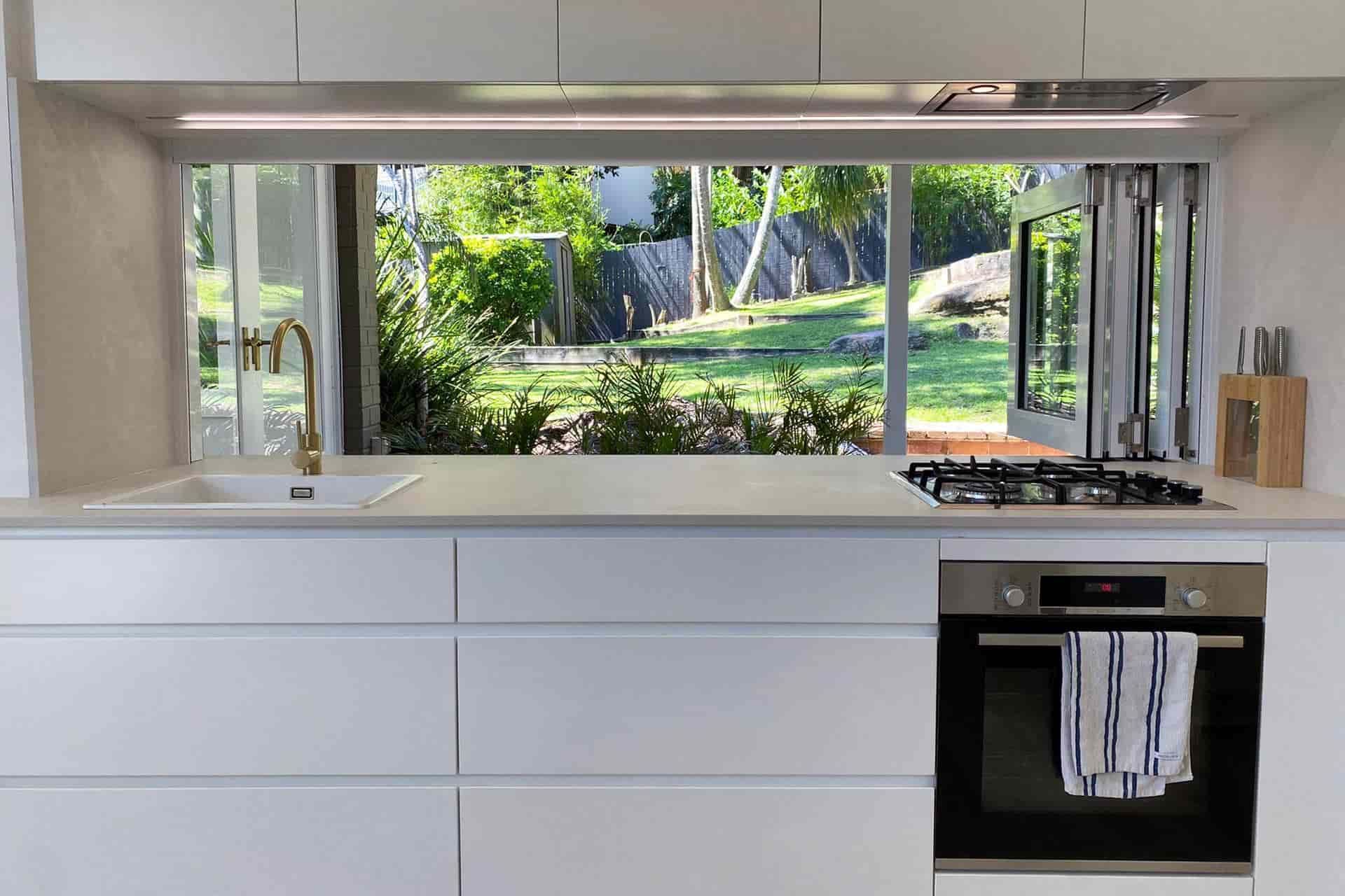 A Kitchen with White Cabinets, a Stove, a Sink, and A Large Window — Blue Horizon Projects in Bateau Bay, NSW
