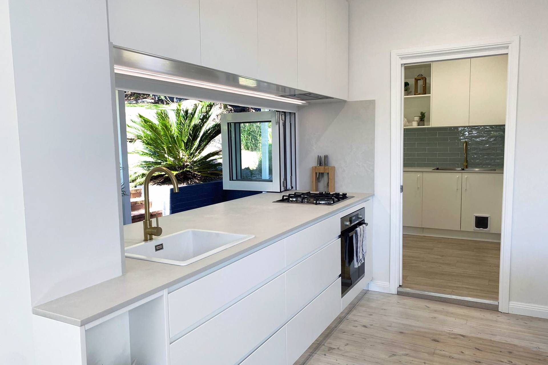 A Kitchen with White Cabinets, a Sink, a Stove and A Window — Blue Horizon Projects in Bateau Bay, NSW