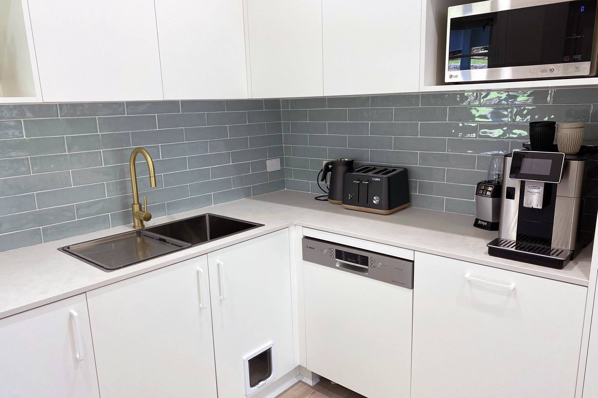 A Kitchen with White Cabinets, a Sink, a Microwave, and A Coffee Maker — Blue Horizon Projects in Bateau Bay, NSW