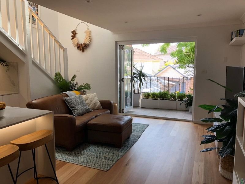 A Living Room with A Couch and Stairs Leading to A Balcony — Blue Horizon Projects in Bateau Bay, NSW