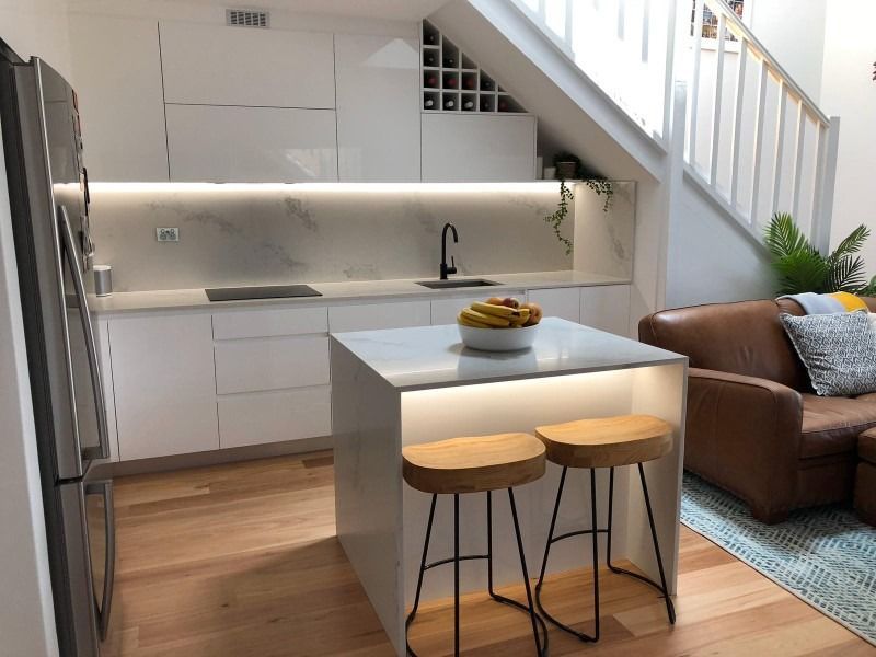 A Kitchen with Stools and A Staircase in The Background — Blue Horizon Projects in Bateau Bay, NSW