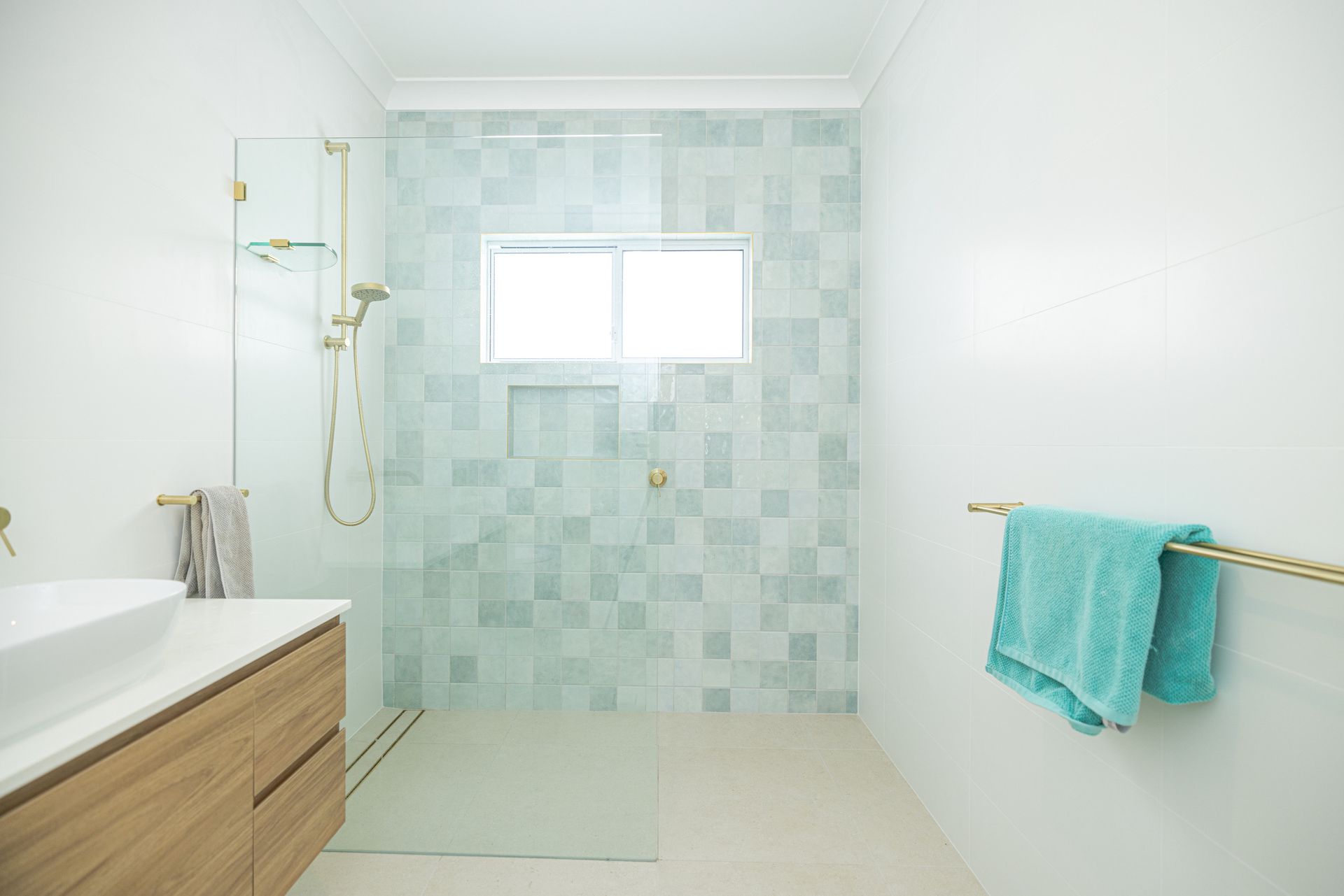 A bathroom with green square tiles and golden features — Blue Horizon Projects in Bateau Bay, NSW