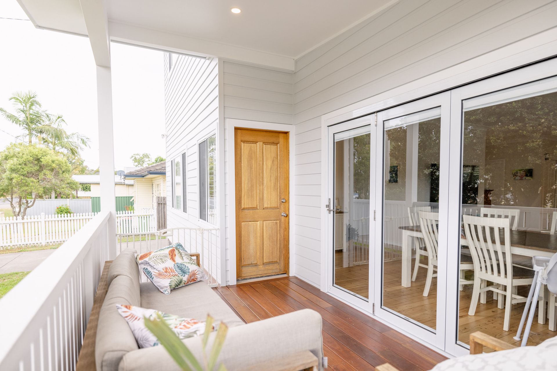 a house front with a wooden door and large glass doors in front of a deck — Blue Horizon Projects in Bateau Bay, NSW