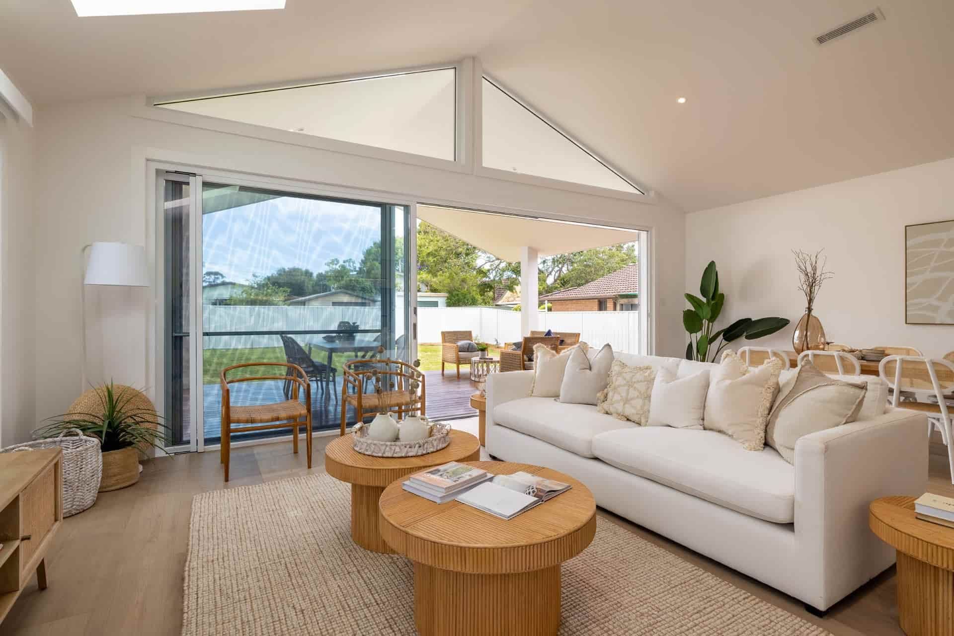A Living Room with A White Couch and Two Wooden Coffee Tables — Blue Horizon Projects in Bateau Bay, NSW