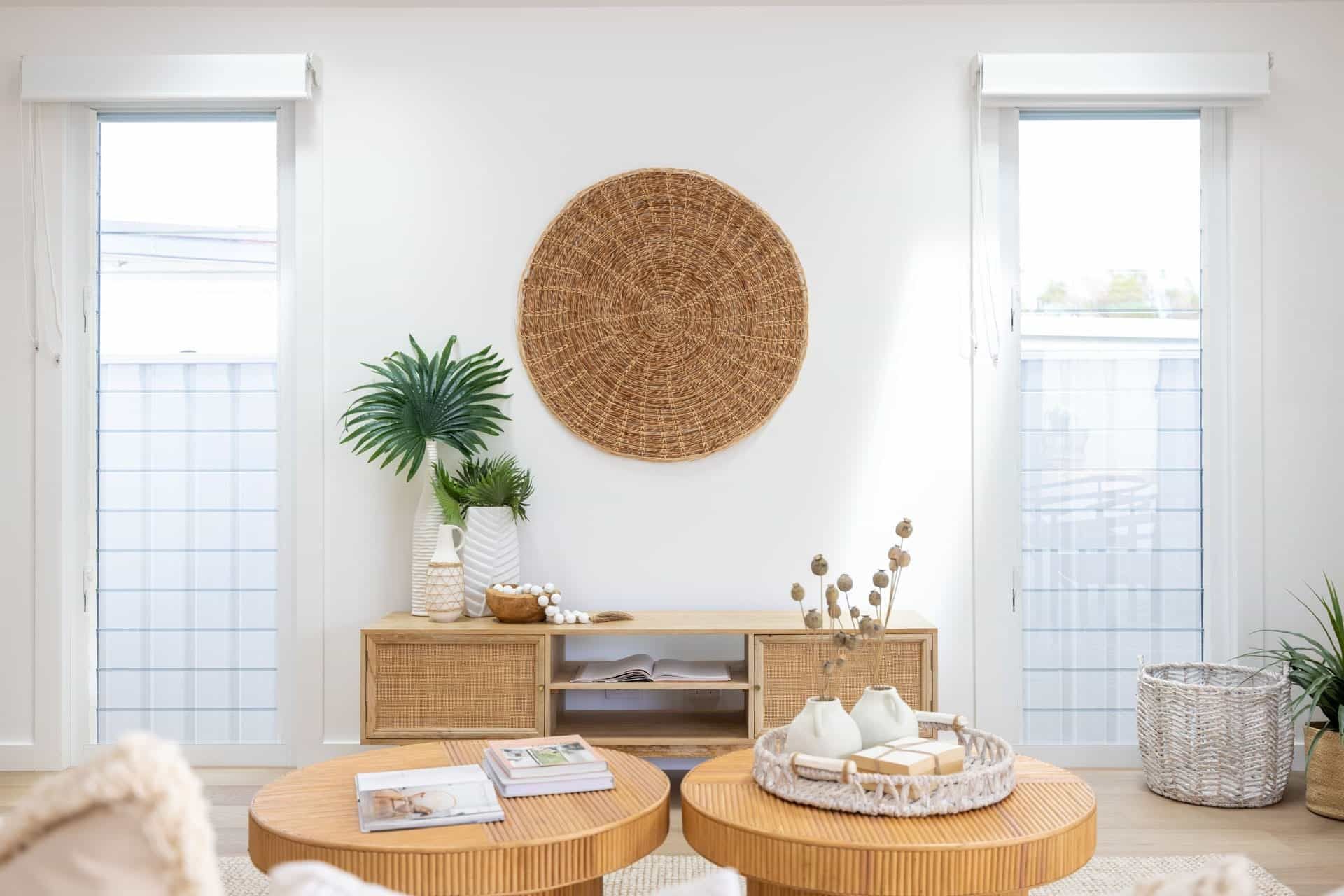 A Living Room with Two Round Coffee Tables, a Wicker Entertainment Center, and A Painting on The Wall — Blue Horizon Projects in Bateau Bay, NSW