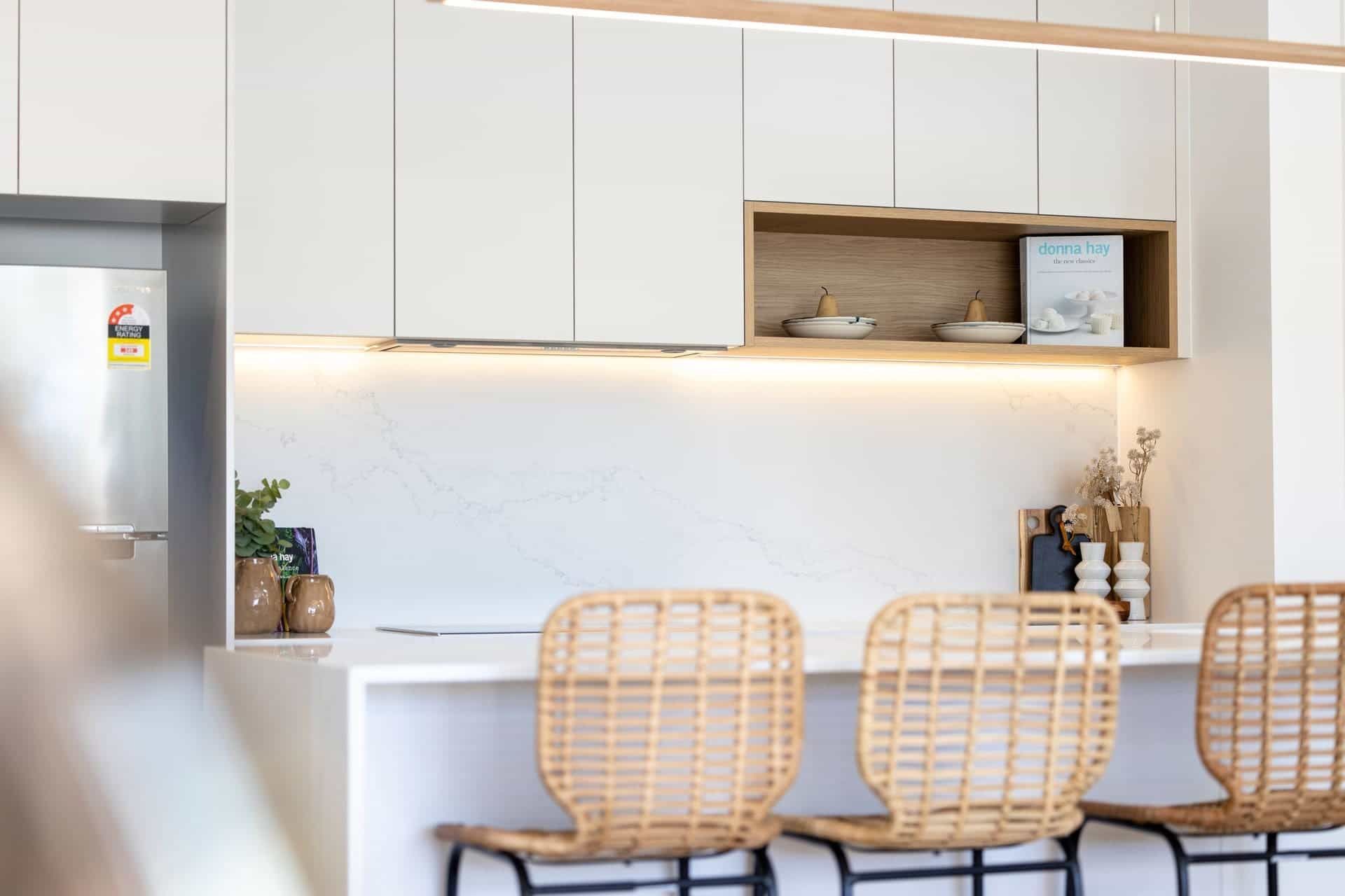 A Kitchen with White Cabinets and Wicker Chairs — Blue Horizon Projects in Bateau Bay, NSW