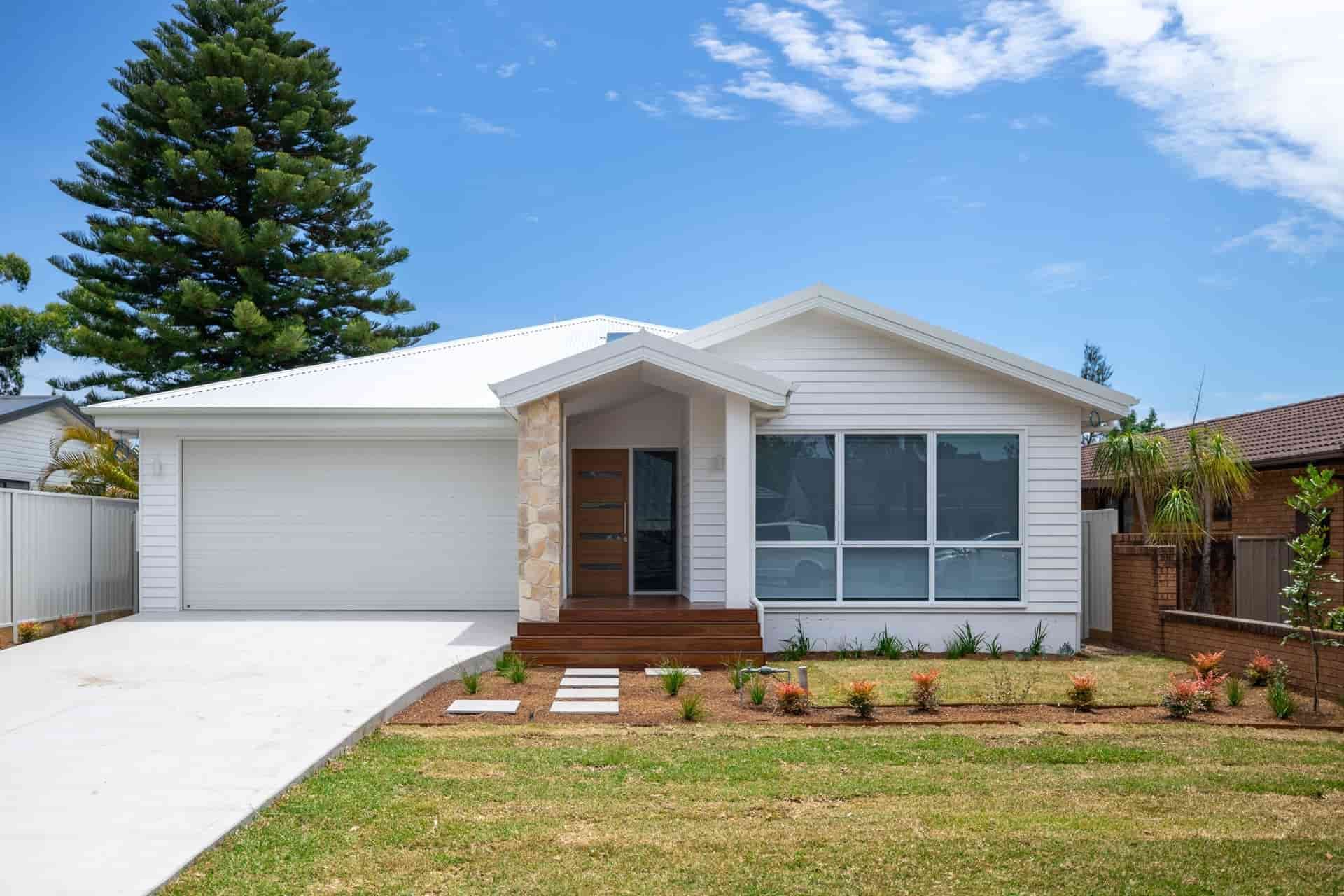 A White House with A Large Driveway and A Tree in The Background — Blue Horizon Projects in Bateau Bay, NSW