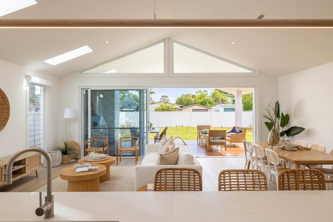 Bright living room opens to backyard, white walls, wood furniture, sliding door, skylight. — Blue Horizon Projects in Bateau Bay, NSW