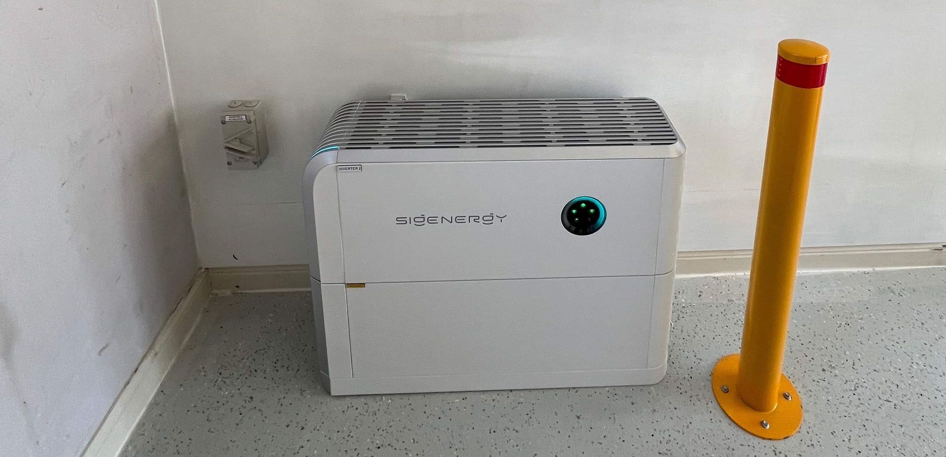 White Storage Unit Wrapped in Plastic Next to a Yellow Bollard, Inside a Corner — Des Mullins Electrical & Solar In Wagga Wagga, NSW