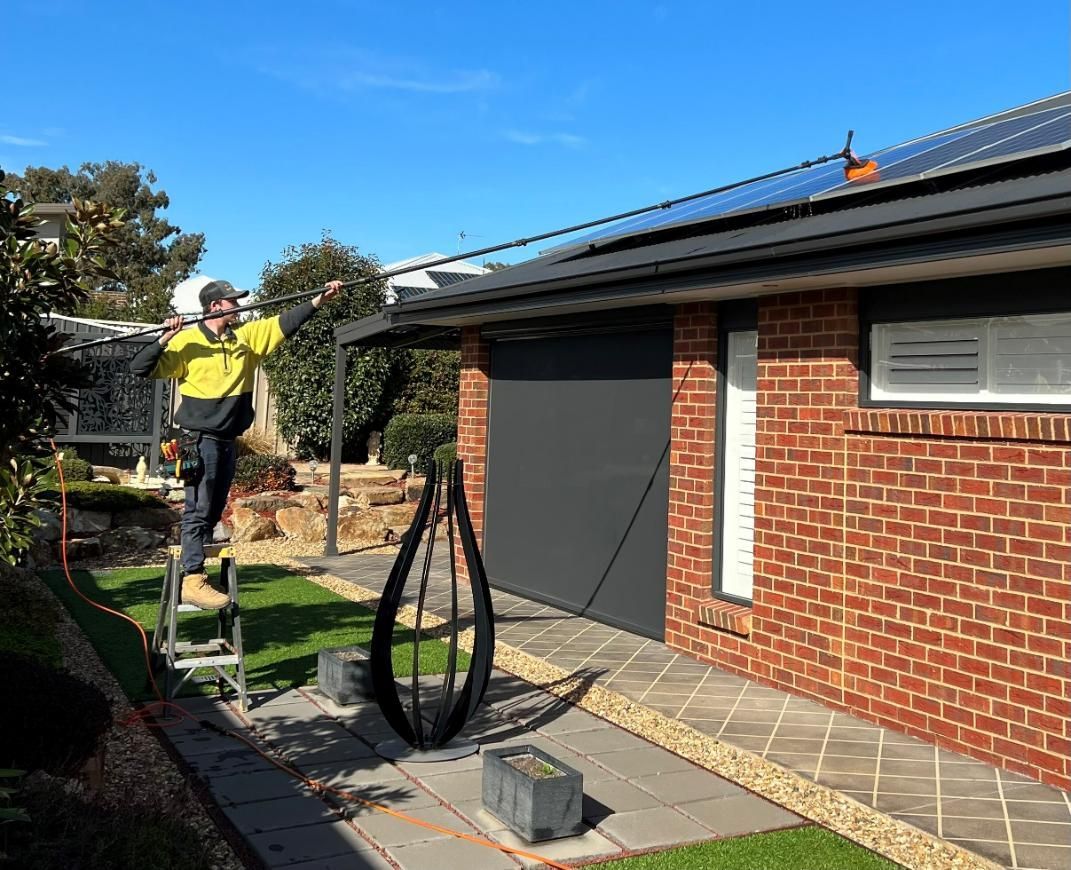 A Man Is Standing On A Ladder Solar Cleaning