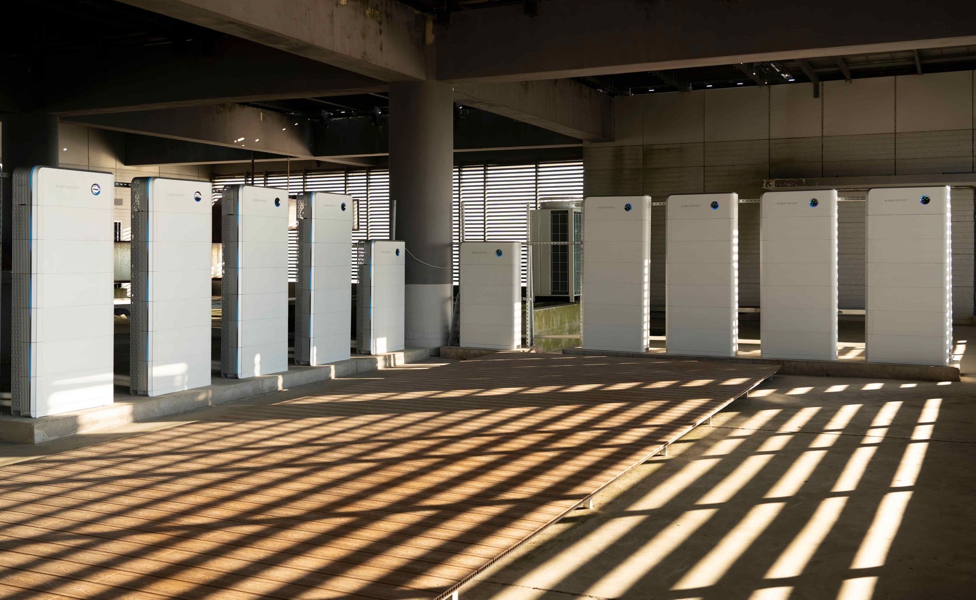 A row of white SigEnergy boxes are lined up in a room — Des Mullins Electrical in Kooringal, NSW