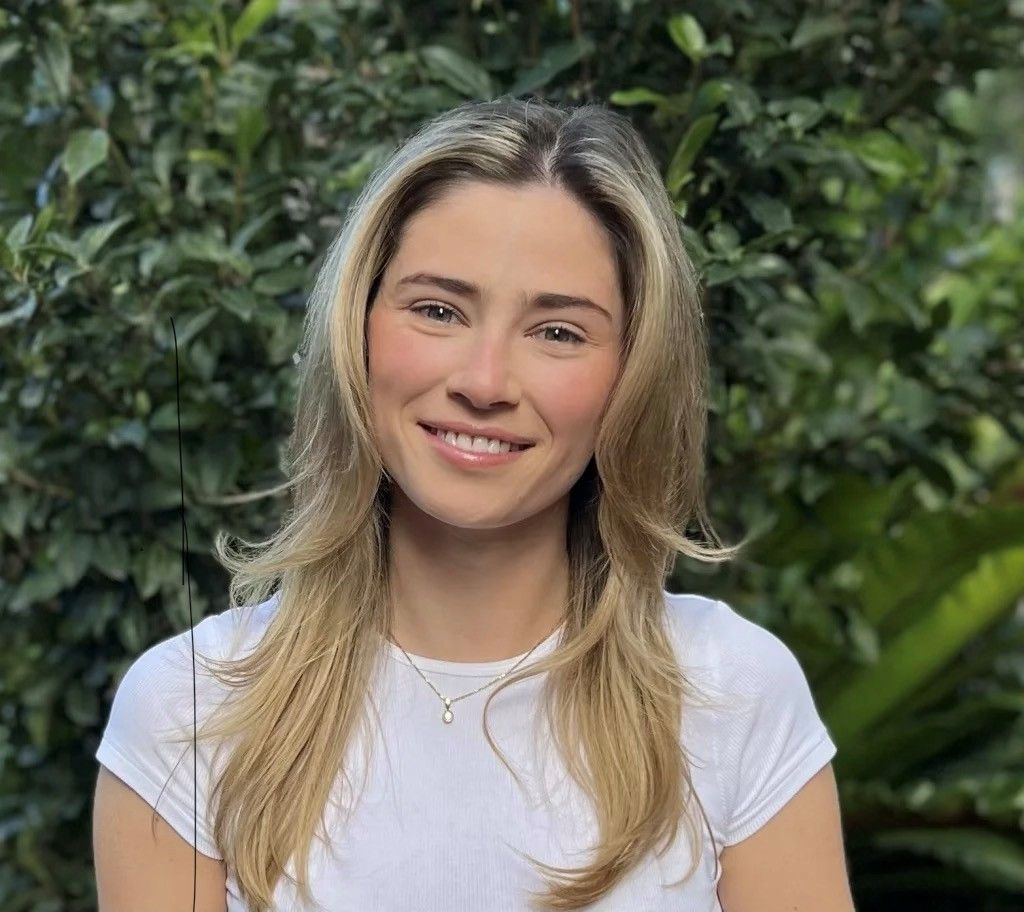 A woman in a white shirt is smiling for the camera