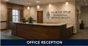 Office reception desk in a warm-lit lobby for Tip of the Spear Thrift National Housing Facility.
