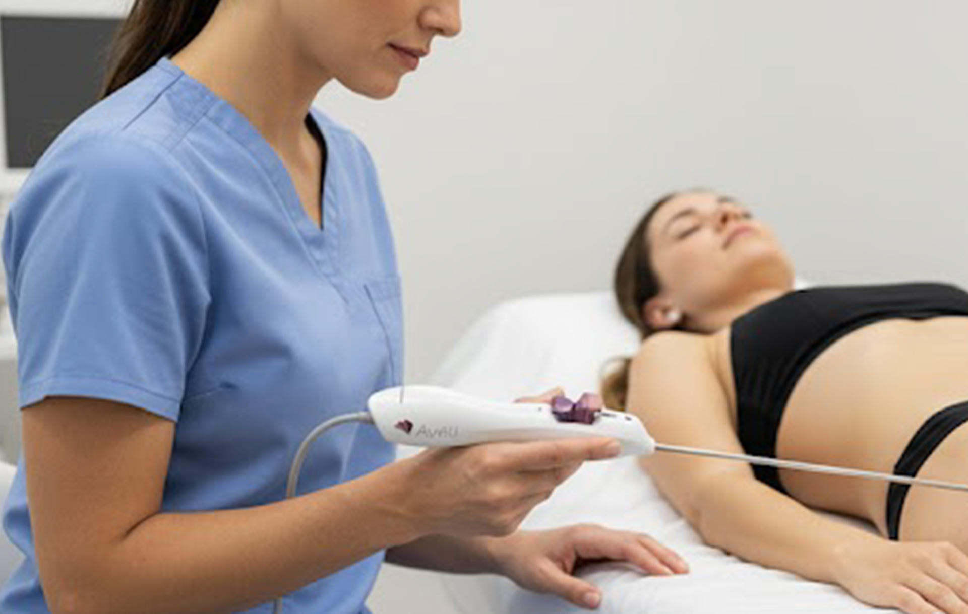 Medical professional using device on patient's abdomen in a clinic.