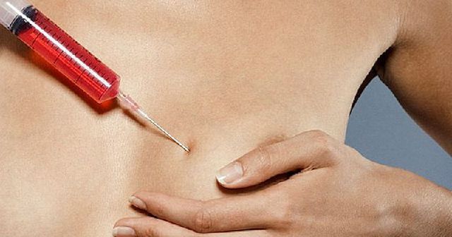 A person's torso with a syringe filled with red liquid, needle pointed toward belly.