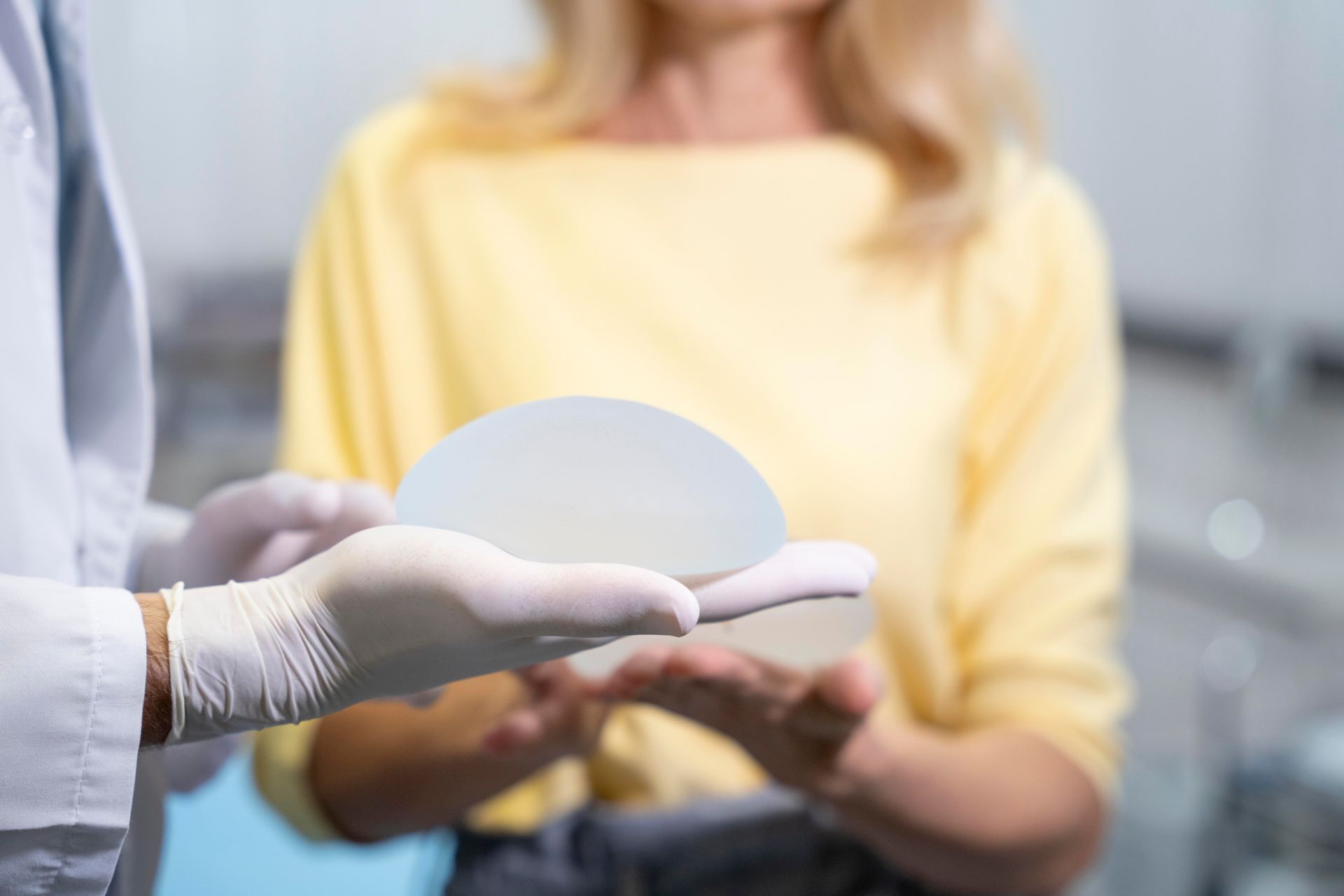 Doctor holding a breast implant, demonstrating it to a patient.