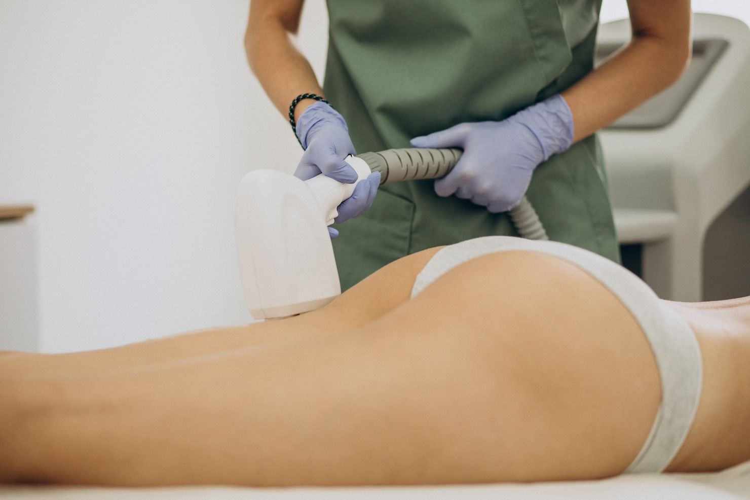 Person receiving body contouring treatment on their buttocks, held by a medical professional.